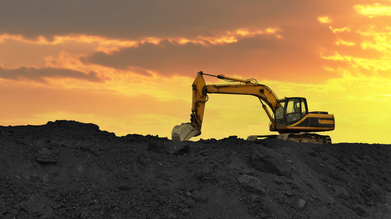 An excavator atop a lithium mine against an orange sky
