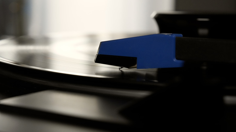Closeup of a record player cartridge and stylus playing a record