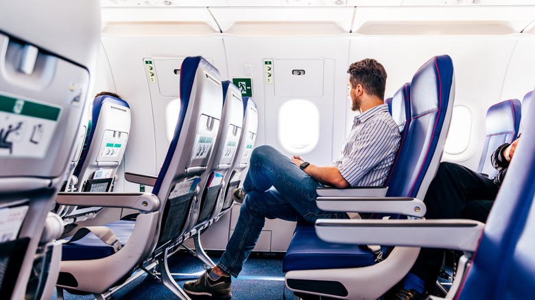 A man sitting in an airplane seat looking out the window