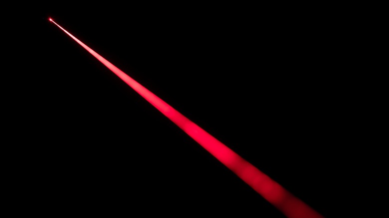 A red laser beam is seen against a black background