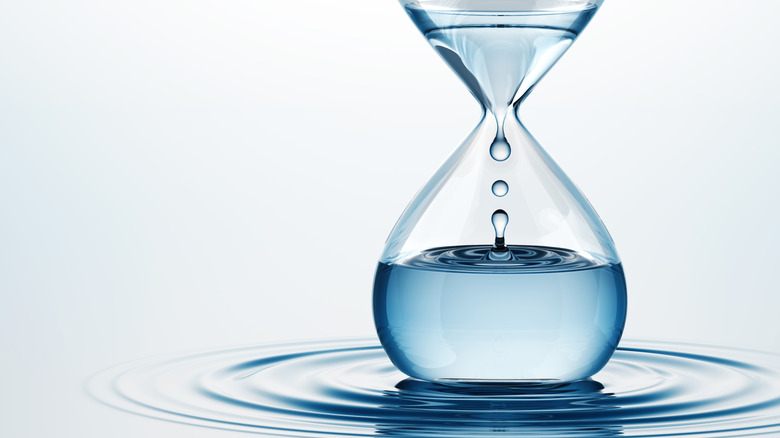Concept of an hourglass of water with water rippling around the bottom