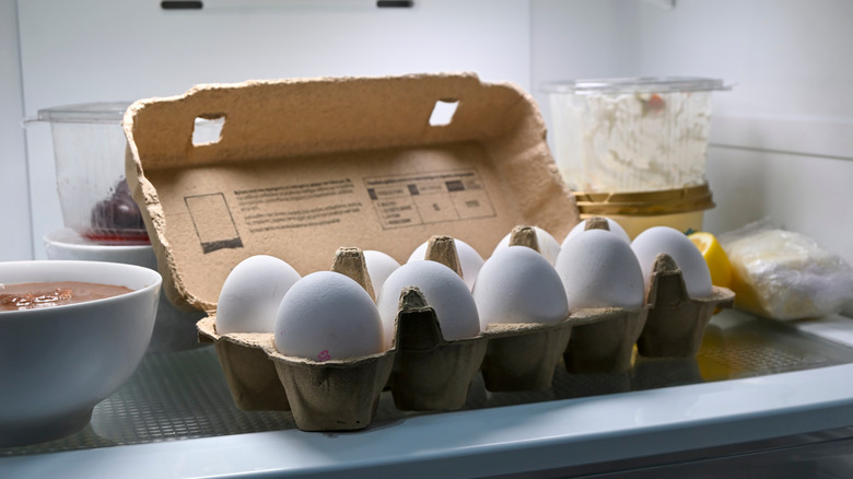 A egg carton full of eggs sits inside a fridge