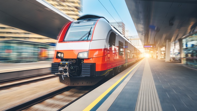 High-speed orange train passing through station