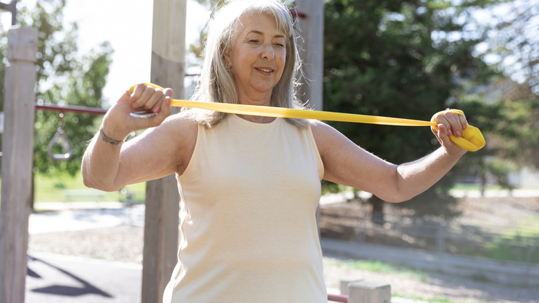 A woman using a yellow resistance band