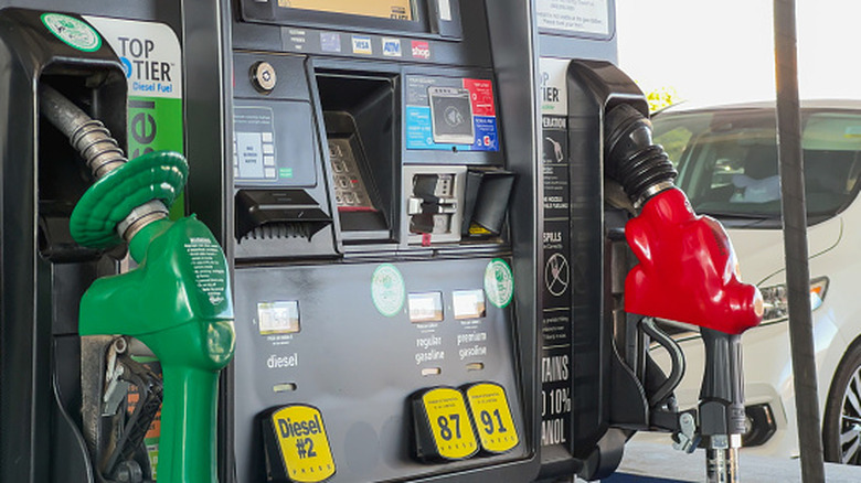 A gas pump with a red pump handle for gasoline and a green pump handle for diesel