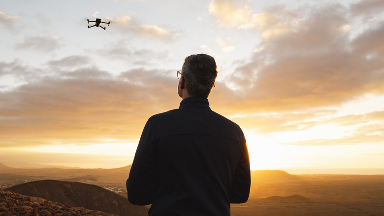 A person operates a drone at sunset