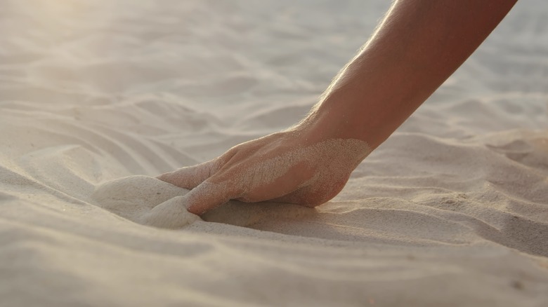 human hand reaching into sand
