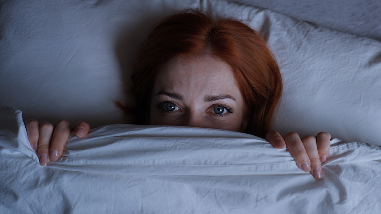 woman hiding under covers