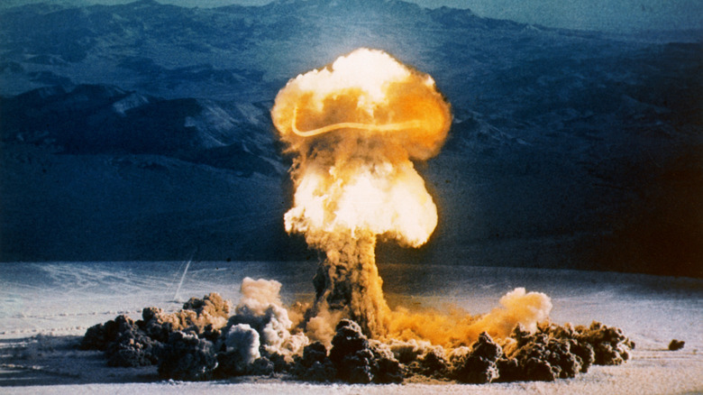 an atomic explosion mushroom cloud captured during Operation Plumbbob with mountains in background
