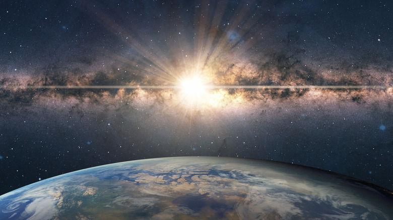 Computer rendering of a supernova explosion occurring in the milky way above a blue earth