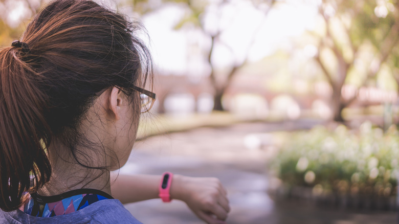 Woman checking smartwatch while exercising outdoors