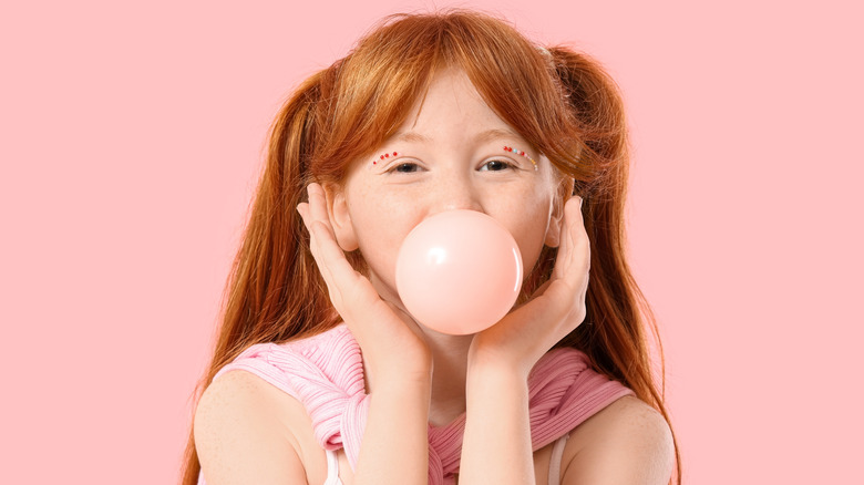 Red headed young girl blowing bubble gum