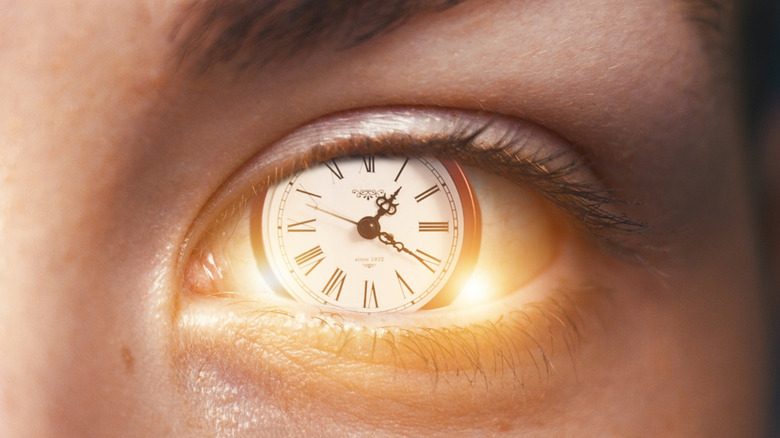 A closeup of a human eye with a clock face embedded in the iris