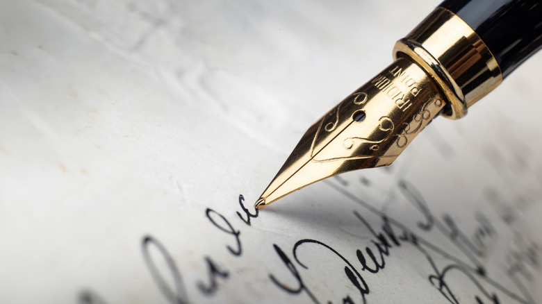 A closeup of a fountain pen writing letters on a piece of paper