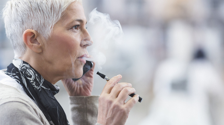 Grey haired senior woman vaping an e-cigarette while on the phone