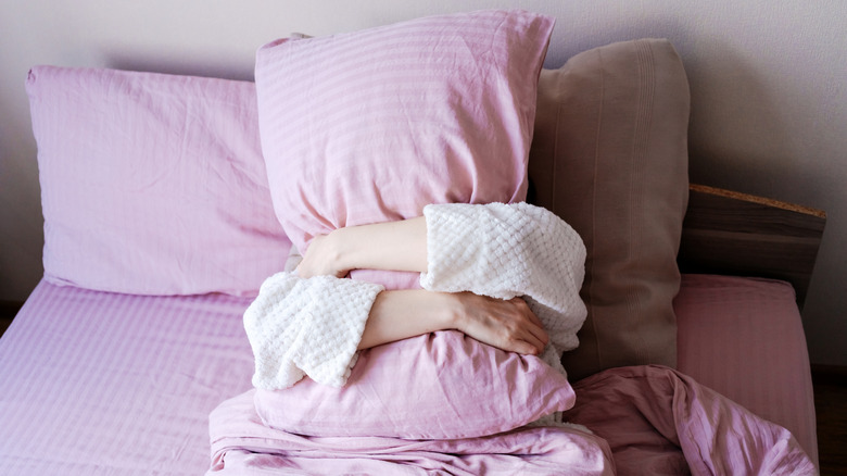 Person hugging a pillow in bed