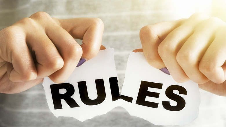 Hands tearing up rules sign