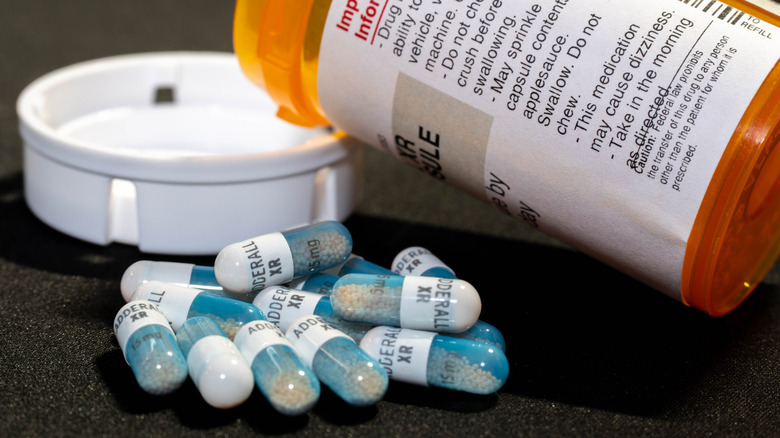 Adderall capsules next to an orange prescription bottle