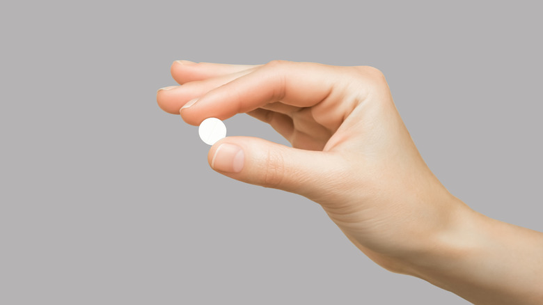 A close-up of a hand holding a pill.