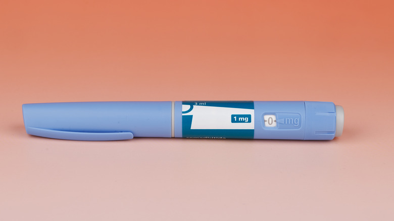 A semaglutide injection pen in front of a peach background.