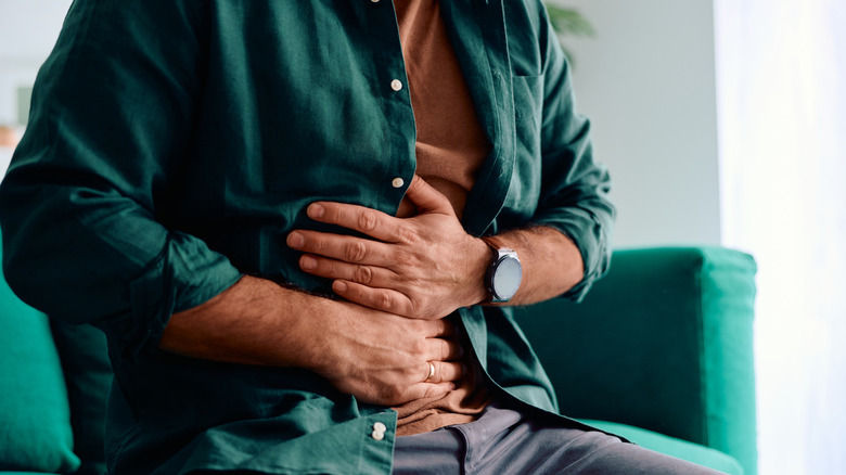 Man holding both hands over stomach in pain
