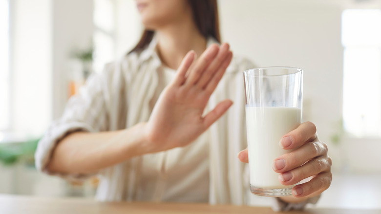 Woman putting up hand to refuse glass of milk