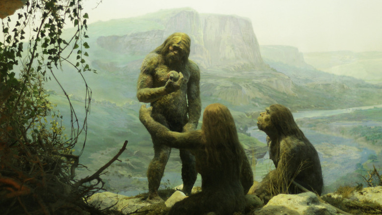 Painting of three ancient wild people looking at a smoothed rock