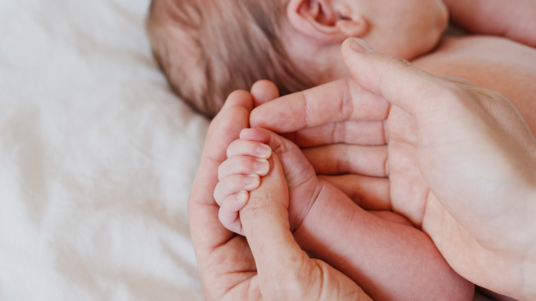 close-up of a newborn baby hand gripping the thumb of an adult hand