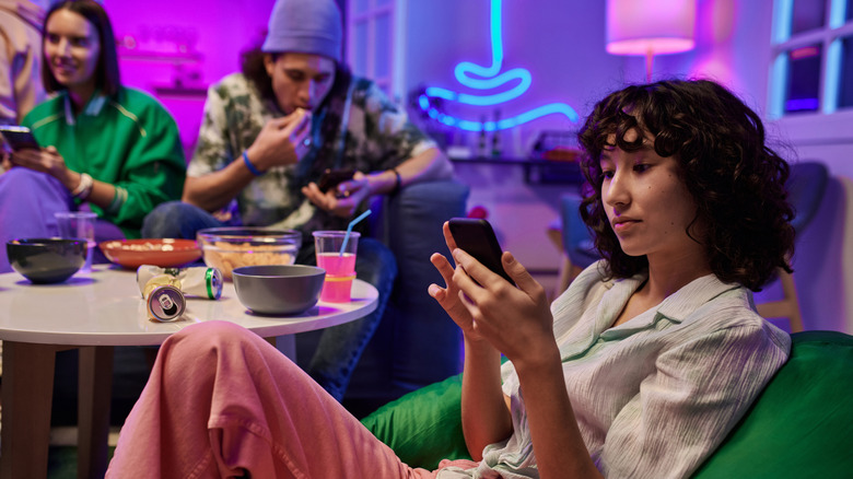 Woman scrolling on her phone during a social gathering
