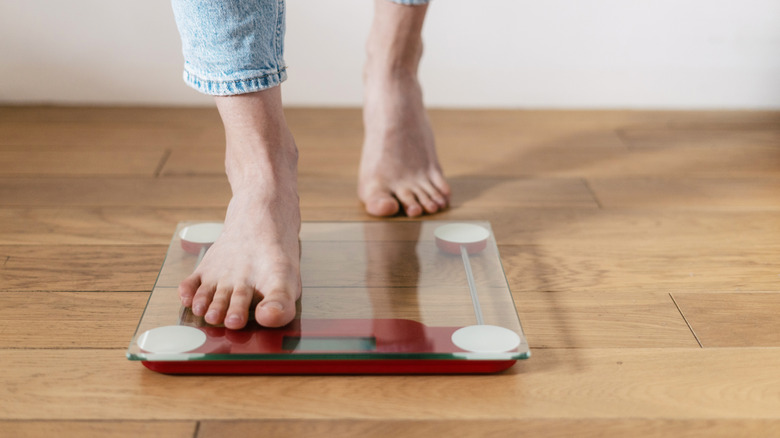 Bare feet stepping on a glass scale