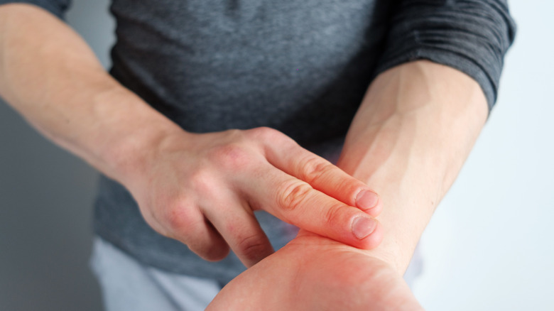 Person pressing two fingers against left wrist, taking their pulse