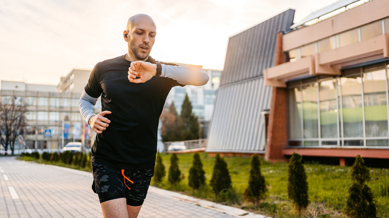 Man looking at fitness watch while exercising outdoors