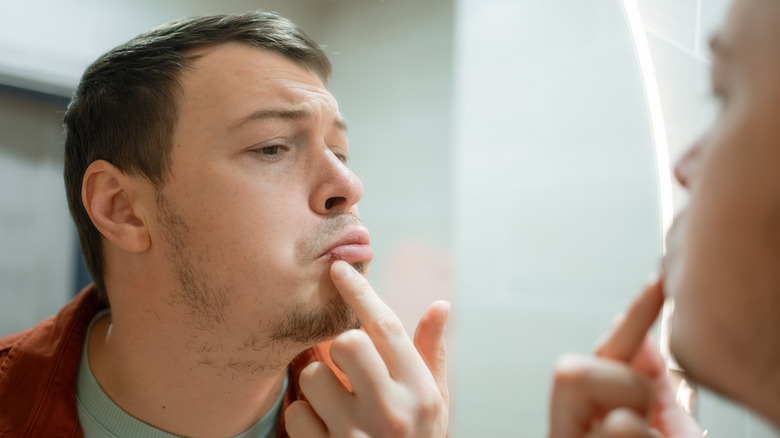 Man examining his lips in mirror