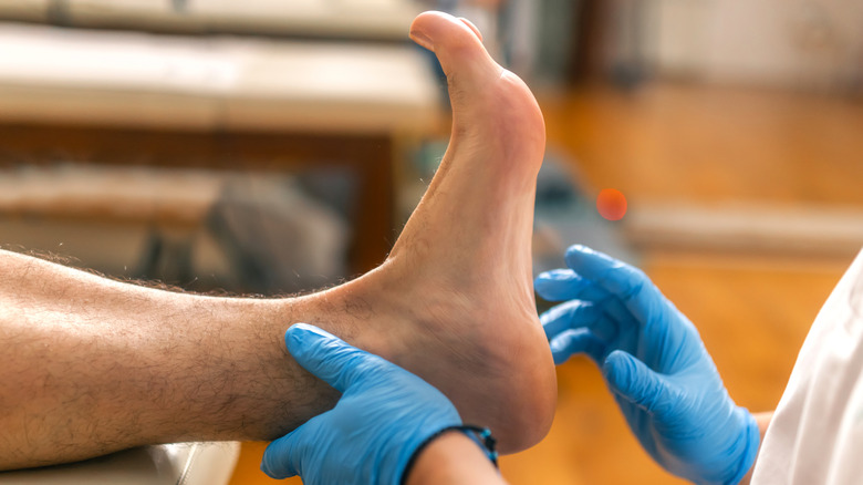 Medical professional wearing blue gloves examines a patient's foot