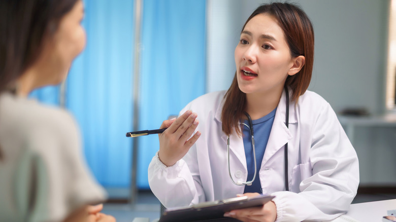 Young female doctor in white coat counseling a patient