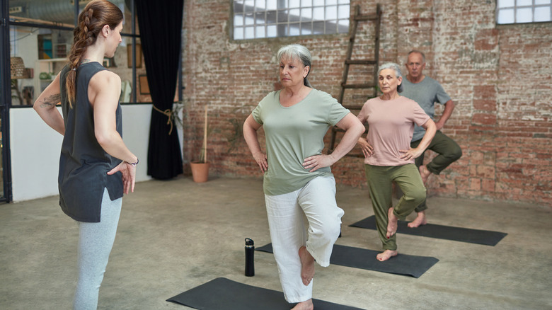 Older adults standing on one leg in tree pose during yoga class