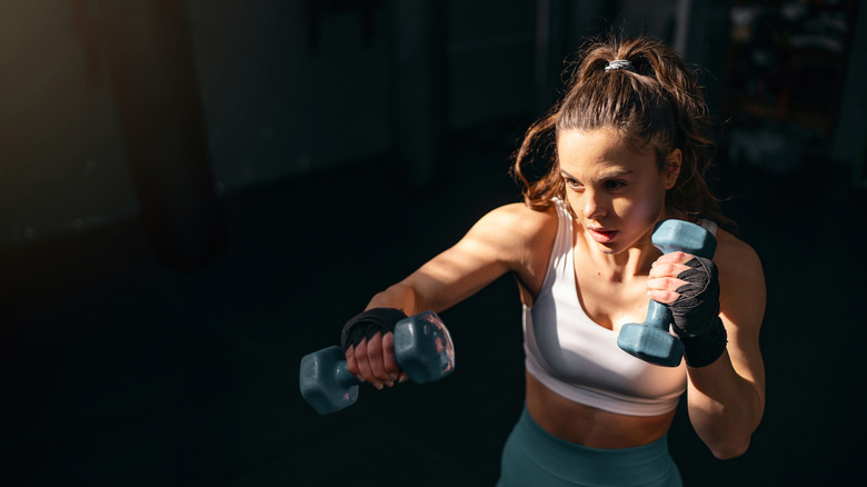 Female athlete shadowboxing with dumbbells