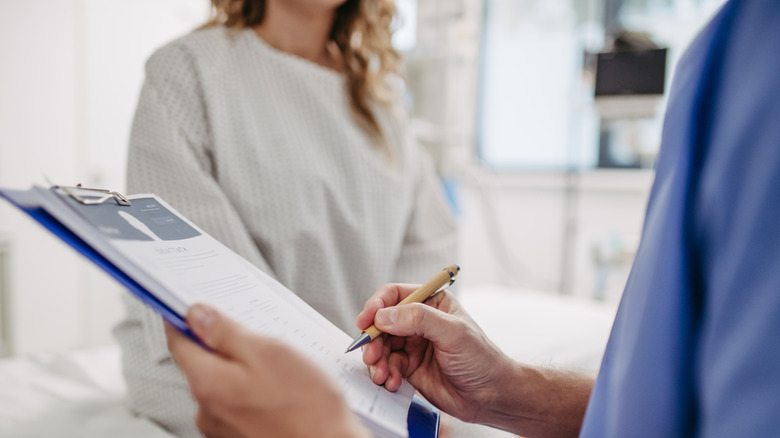 Patient talking with a health care professional holding a clipboard