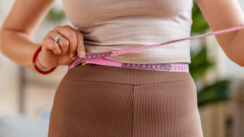 Woman measuring circumference of waist