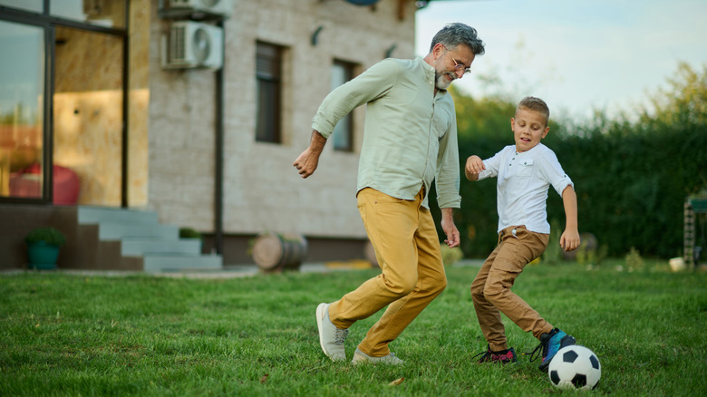 Father and son play soccer outside of home