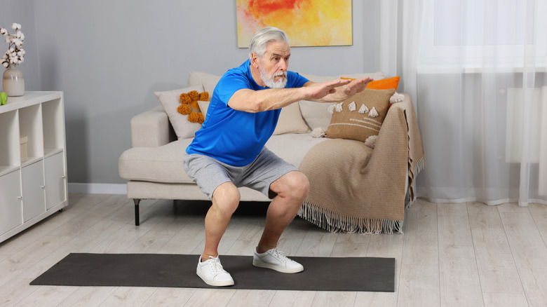 Senior man standing up from squat