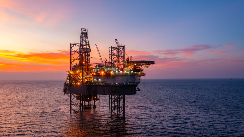 An image of an oil rig in the ocean at sunset