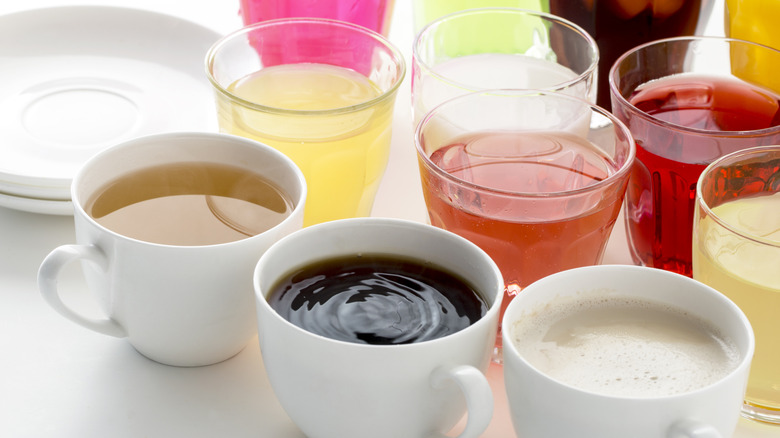 A variety of different drinks in glasses and cups, coffee in the center