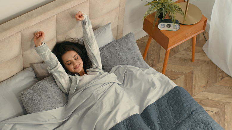 Woman in bed waking up and stretching