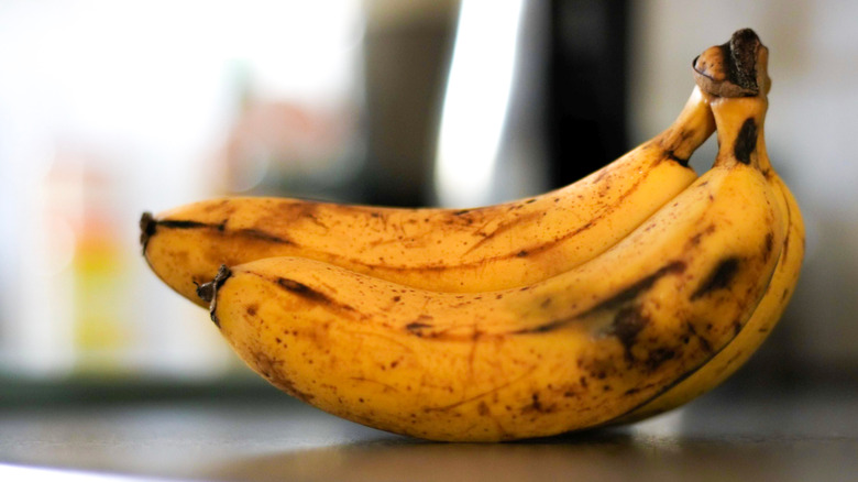 Bruised bananas on a countertop with a blurred kitchen background