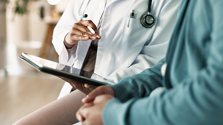 Doctor consulting with patient while holding clipboard