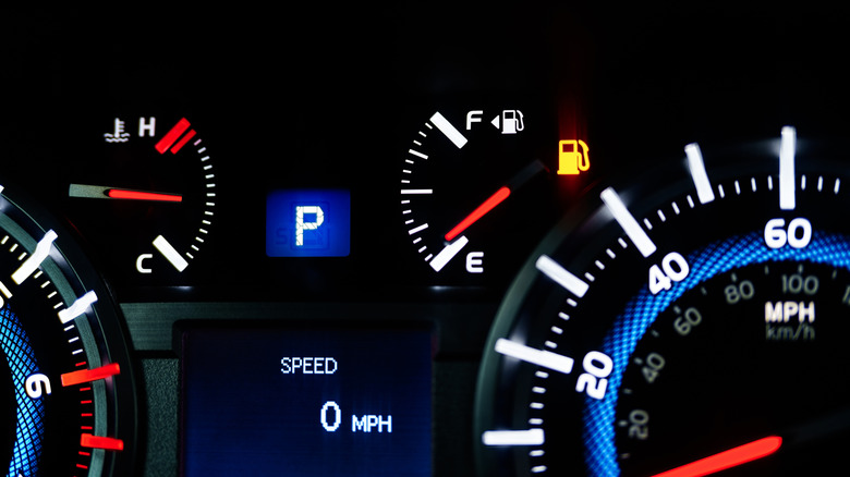 illuminated car dashboard showing fuel gauge at nearly empty