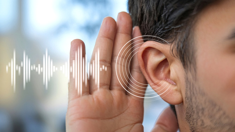 Man raises his hand to his ear as an overlayed graphic of sound waves passes over