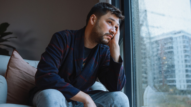 Man with head in hand while looking out window