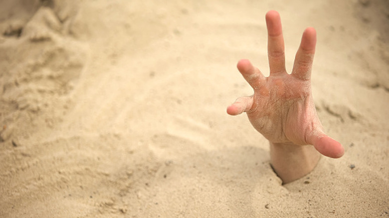 Hand sticking up out of sand